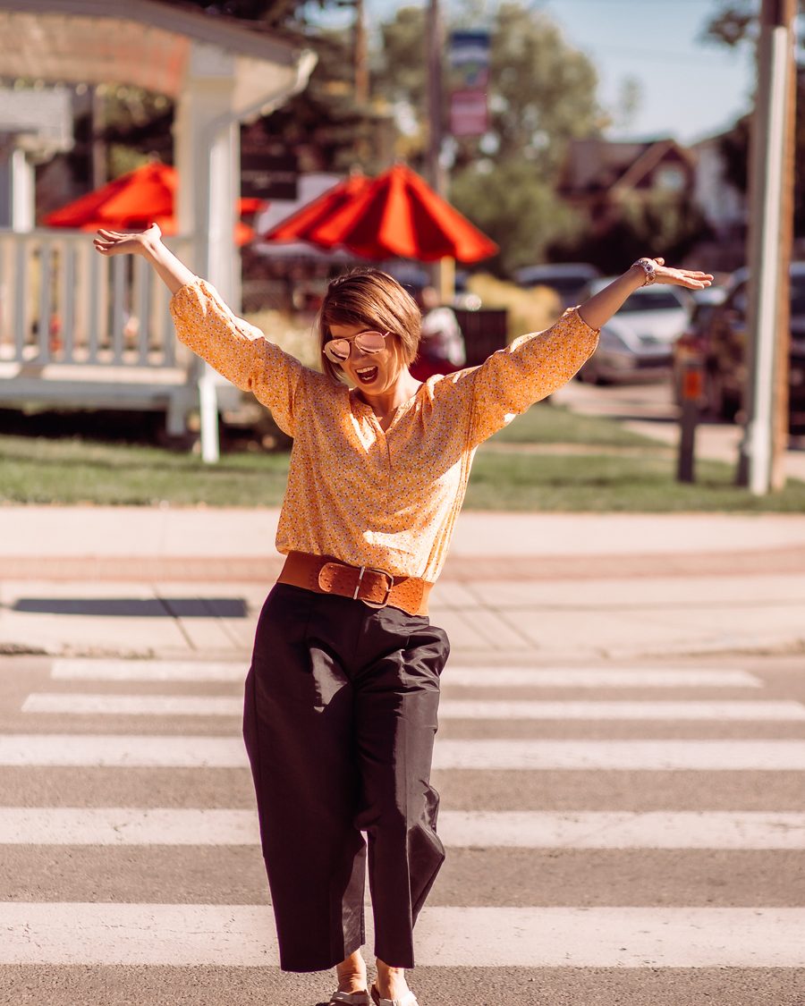 Kelly on a crosswalk with her arms in the air